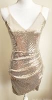 Front view of the sparkling gold sequin mini dress displayed on a mannequin showing V-neck, spaghetti straps, and side ruching.