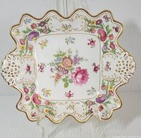 Front view of square bone china dish showing hand-painted colorful floral Dresden sprays and gold gilded edges and handles.
