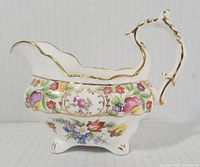 Side view of bone china creamer showing colorful floral Dresden sprays and scalloped gold rim.