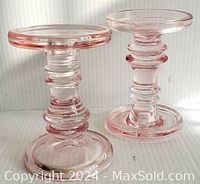 Two pink glass candleholders shown from front and side angles, highlighting size, shape, and color.