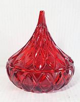 Front view of vintage ruby red crystal trinket box shaped like a Hershey Kiss with intricate facets.