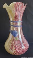 Full view of the vintage Murano art glass vase showing its mottled red and yellow coloration, fluted top with chip, and blue glass band accents.