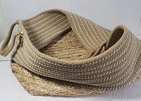 Close-up photo of the basket showing the cotton woven handles and part of the straw base and body.