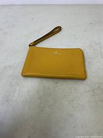 Mustard yellow Coach wrist wallet front view on plain surface