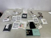 Overview of the costume jewelry lot showing all items arranged on a table including packaged jewelry and pouches.