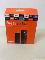 Front view of the sealed orange retail box for Amazon Fire TV Stick Lite showing images of the device and remote, and streaming service logos.
