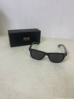 Luenx black frame polarized sunglasses displayed next to the black branded box.