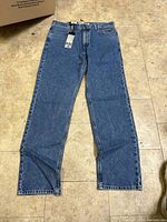 Full view of men's blue denim jeans laid flat showing size and style.