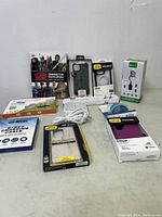 Photo shows a collection of new electronic accessories and a Star Wars book laid out on a table, including Otterbox phone cases, earbuds, charging cables, and an adapter.