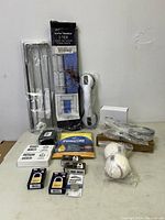 Full view of all items included in the lot, showing packaged towel rack, cordless phone, batteries, poncho, and other items.