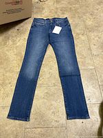 Full front view of the men's denim jeans laid flat on the floor, showing color, cut, and condition.