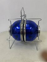 Blue pet food and water bowls attached in foldable silver metal carrier, folded and upright