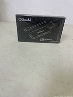 Photo of the sealed QGeeM USB-C 4-Port Multifunction Converter box, showing product branding and design.