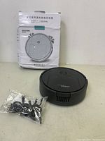 Front view photo showing the Xileshu mini sweeping robot vacuum, packaging box, and accessories in sealed bag.