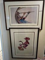 Two framed prints by David Kabuuka shown hanging on a wall, artwork features abstract African figures