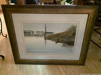 Full view of watercolour artwork framed in large gold-toned wood frame on hardwood floor