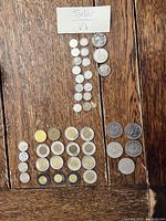Coins laid out on wooden surface showing silver coins in top center, toonies in bottom middle, loonies to right, and other coins grouped.