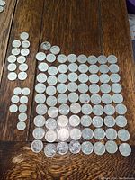 Full layout of 72 Canadian special quarters, plus several older dimes and nickels spread on wooden surface