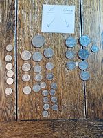 Coins arranged in separate US and Canada groups on wooden surface, showing different denominations and sizes.