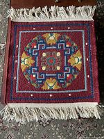 Top-down view of the square prayer rug showing the full geometric and floral pattern with white fringes.