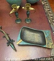 Lot contents including brass ashtray, brass alligator nutcracker, and pair of brass candlesticks with green patina