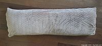 Front view of rectangular chenille fabric body pillow with chevron textured pattern on beige fabric.