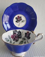 View of cup and saucer with cobalt blue surrounding and floral rose centerpiece