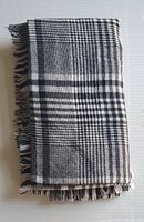 Folded black and white checked blanket showing fringe on one edge.