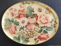 Top view of an oval vintage 1970's fiberglass serving tray showing colorful floral and fruit pattern with gold edge trim.