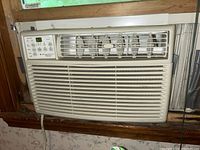 Frigidaire window air conditioner installed in window showing overall unit with vent grilles and controls on the left side.