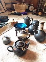 Full group of artisan pottery pieces including teapots, jug, vase, and blue bowl