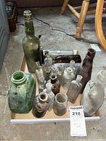 Box with approximately 14 dusty vintage bottles of assorted sizes and colors.