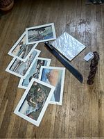 Wide view showing machete, art prints, and a coiled carved sculpture on wooden floor