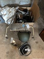 Box of chrome side mirrors, green helmet, and mounting parts arranged on the floor.
