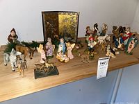 Full nativity set with Holy Family, animals, shepherds, Wise Men, angels, and decorative backdrop on wooden table.