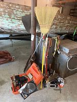 Full view of assortment including buffer, brooms, shovels, and plugs in garage setting