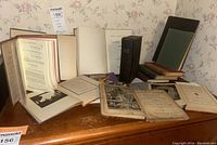 Collection of vintage and antique books spread out on a table showing various sizes and conditions.
