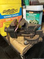 Full side view of the Pulto diamond bench vise showing mount and workspace background.