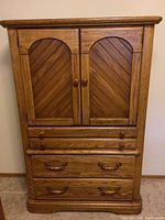 Front view of the tall wooden dresser showing the cabinet doors, drawers, and handles.