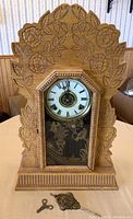 Front view of the carved wooden clock with floral and leaf carvings around the face and glass.
