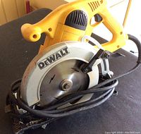 Close-up photo of Dewalt circular saw showing the blade guard, handle, and coiled power cord.