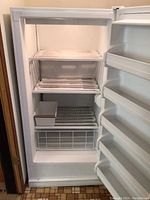 Interior view of the upright freezer showing three wire shelves and four door shelves.