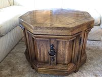 Front and side view of the hexagon wooden cabinet table showing paneled door, metal handle, textured wood grain surface and beveled edges
