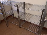 Set of 2 metal wire shelves side by side against a wall, each with three wire tiers, chrome finish, open design.