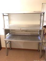 Full view of the industrial style stainless steel shelf showing its overall height, width, and construction.