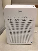 Front view showing Winix logo above perforated air intake panel designed with gradient dot pattern.