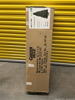 Closed box containing the 9 foot artificial Christmas tree labeled Current Garden Christmas Tree, not prelit.