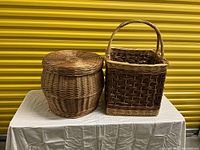 Photo showing two large floor baskets, a round basket with lid on the left and a square basket with handle on the right.