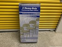 Box of 4 Heavy-Duty Commercial Steel Folding Chairs showing product image and description on the packaging.