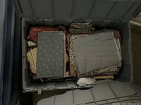 First box containing folded pieces of fabric in muted tones including gray with tiny white dots, brown leopard print, and textured beige fabric.